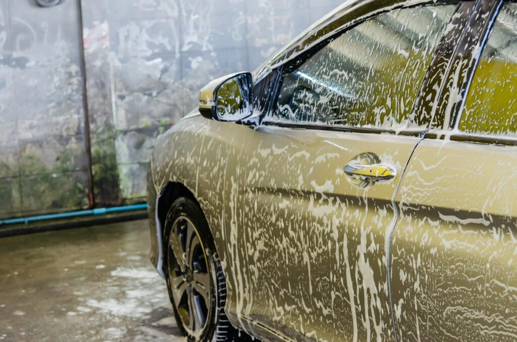 A car being washed with soap at a car wash service, highlighting cleaning and care.
