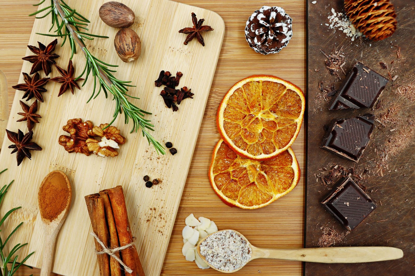 Top view of assorted spices, dried oranges, and chocolate on wooden boards, perfect for winter recipes.
